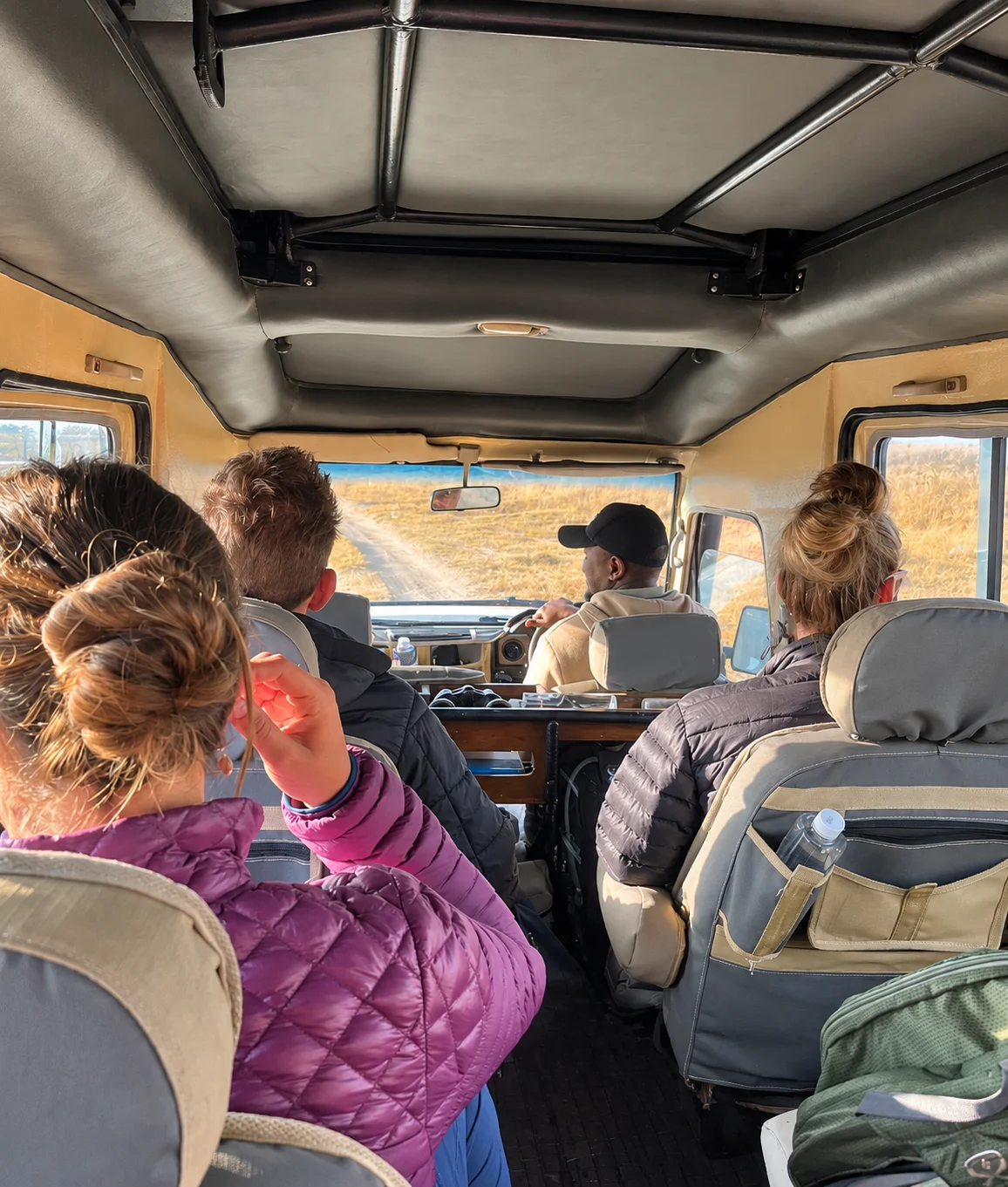 Travelers and their driver-guide journeying through Tanzania in a safari vehicle