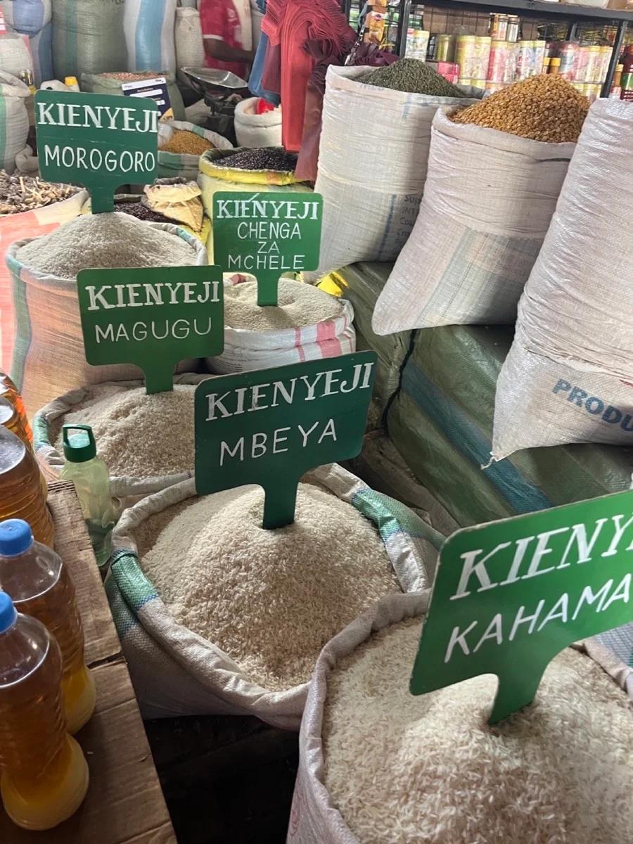 Open rice sacks labeled by Tanzanian growing regions at a local market
