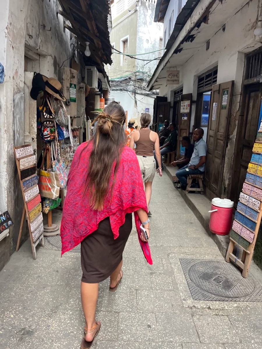 Local residents and visitors along a narrow street in Stone Town